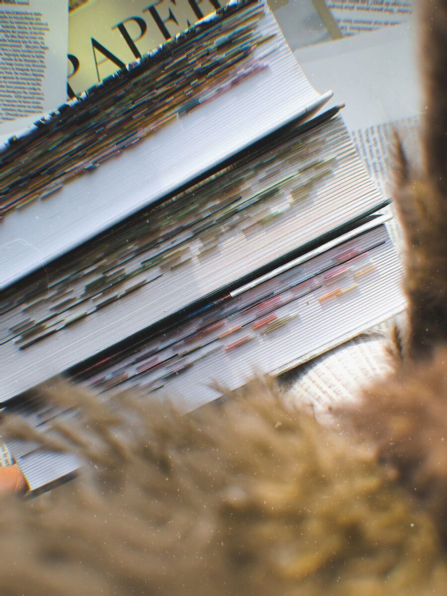 Diagonal stack of glossy magazines with colorful spines and visible text, partially blurred in the foreground.
